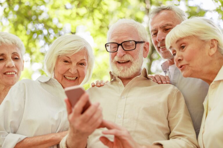 Uśmiechnięci starsi ludzie używający telefonu komórkowego na ulicy