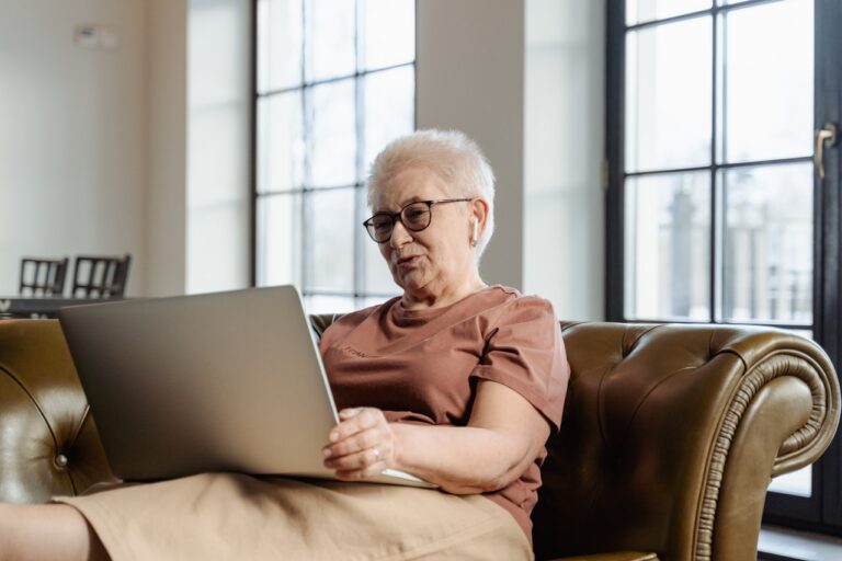 Seniorka z laptopem na sofie