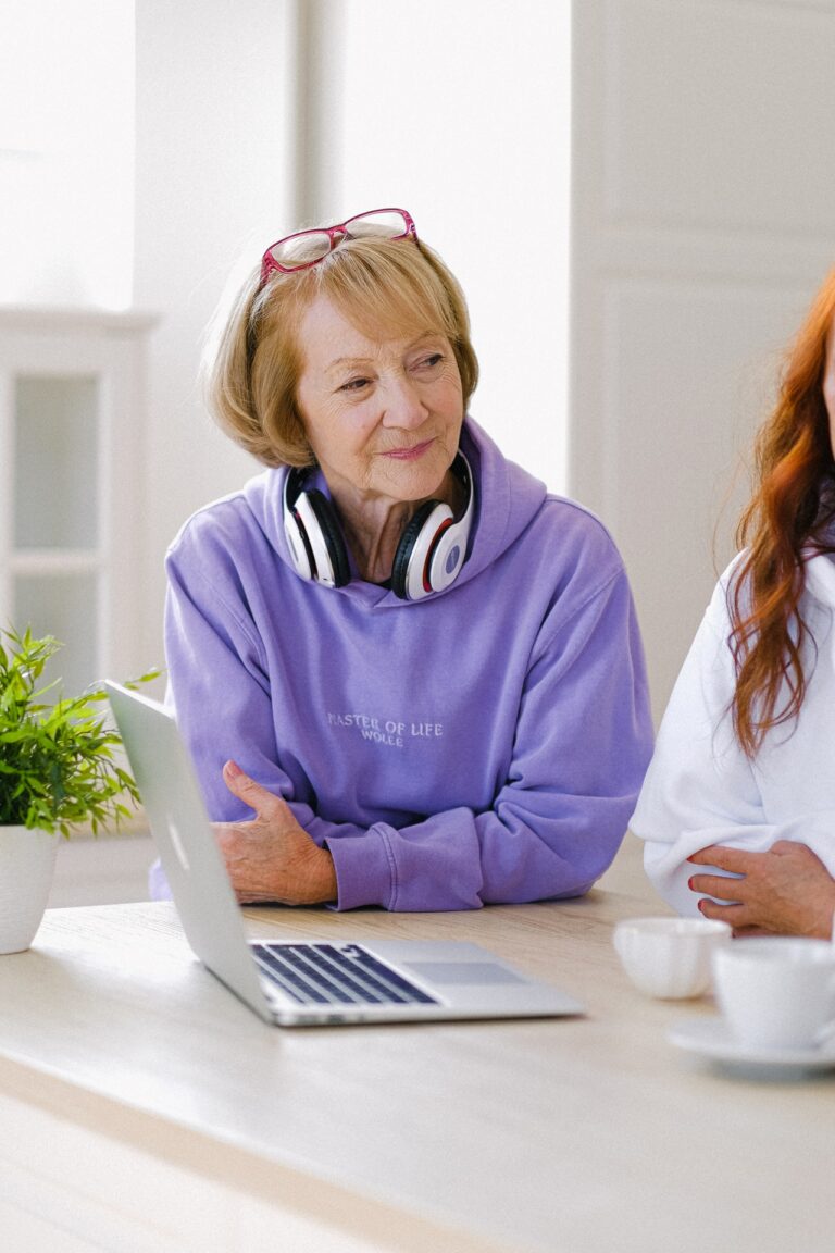 Seniorka ze słuchawkami i z laptopem